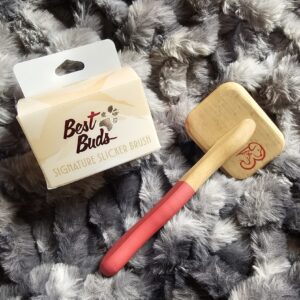 Best Buds Signature Slicker Brush with wood handle and red grip on gray fur background